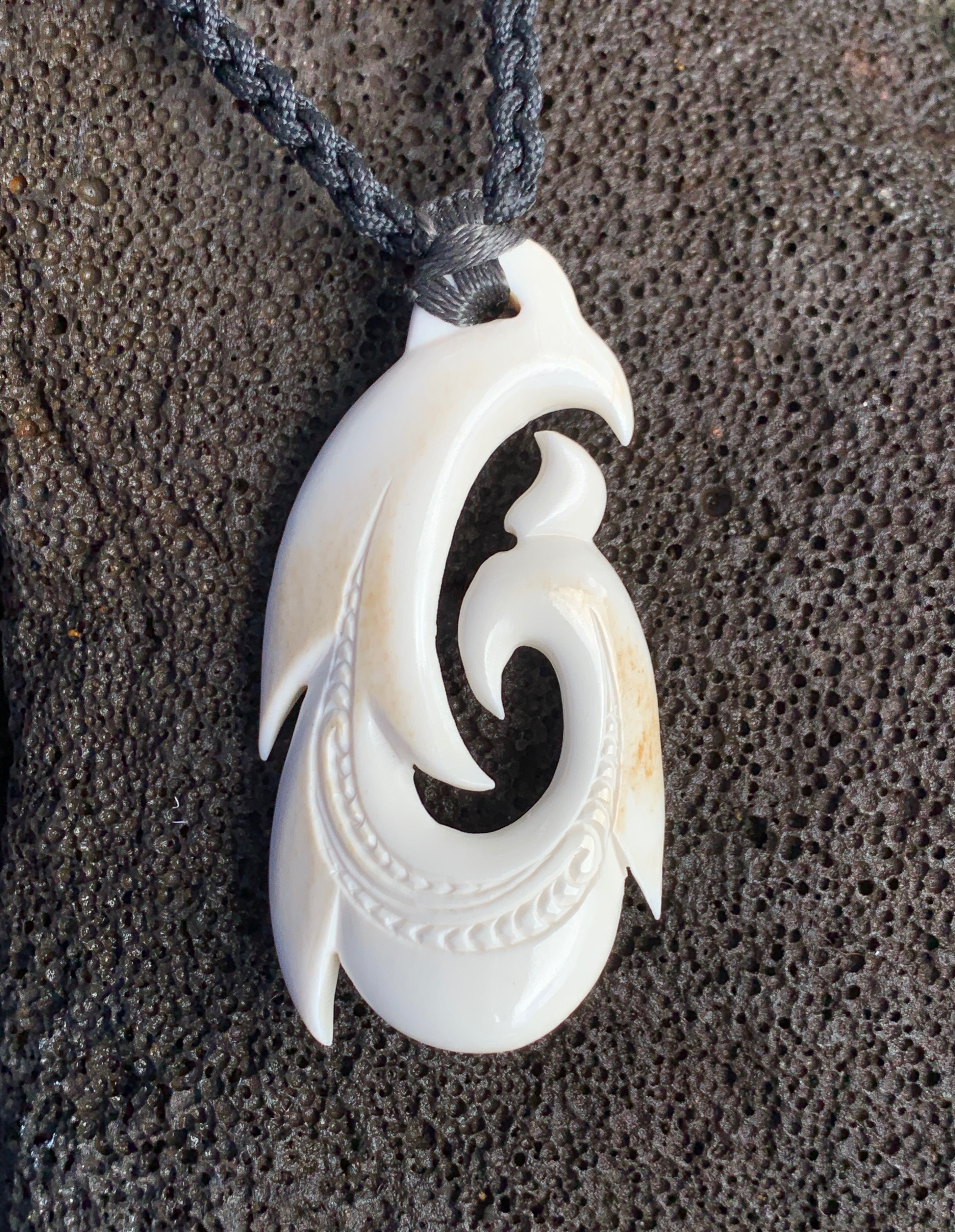 Hand-carved bone pendant on dark surface